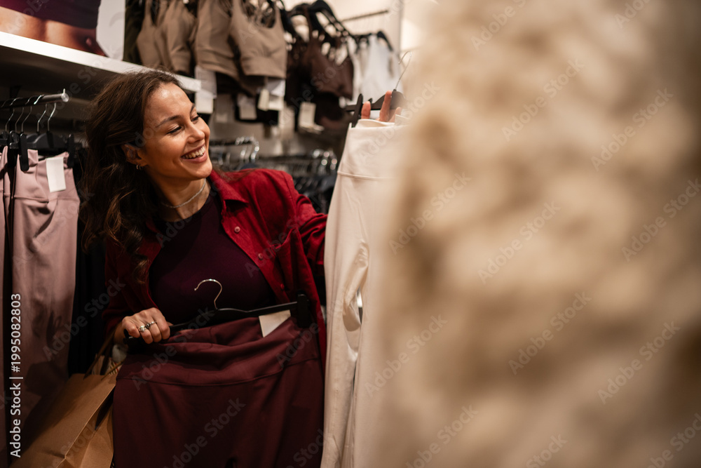 Fototapeta premium Happy woman shopping for clothes browsing retail store