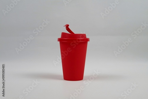 Red plastic coffee cup with lid on a white background, minimal studio composition representing takeaway coffee concept.