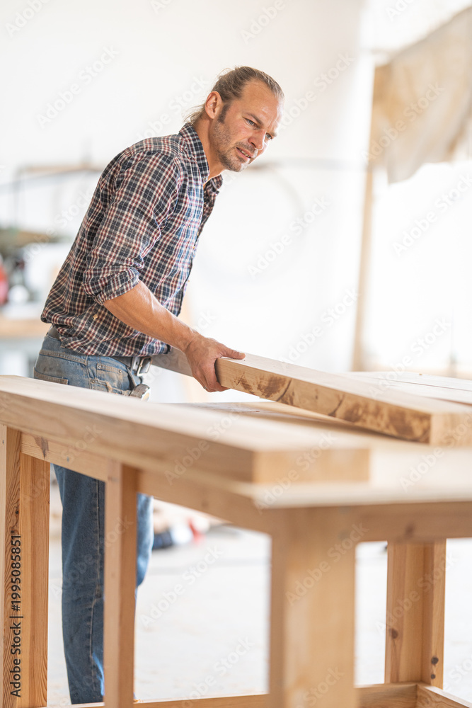 Fototapeta premium Carpenter working with wood plank in workshop