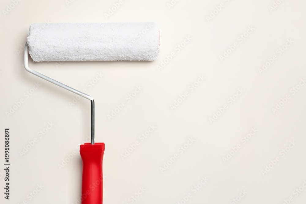 Obraz premium Roller Brush With White Cover Rests on Plain Wall With No Other Items Around in Interior Space