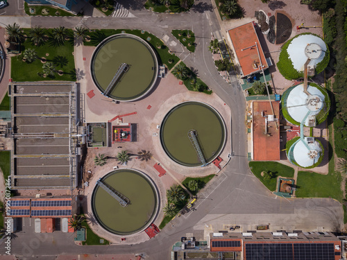 фотографія Top-down view of urban wastewater treatment plant showing three circular seconda