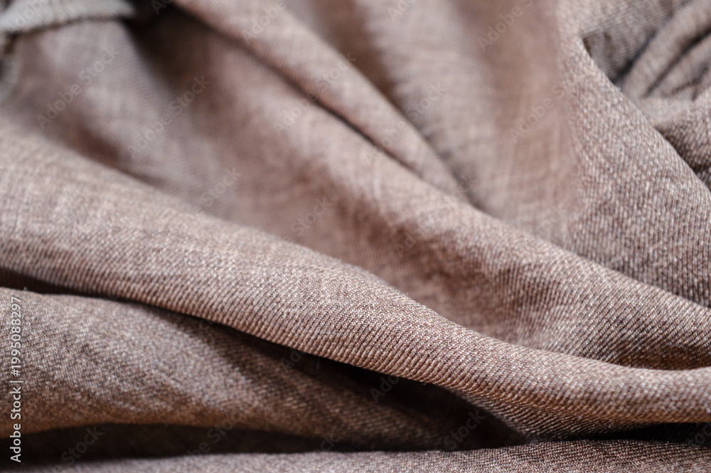 Fototapeta premium Close-up of wrinkled brown fabric folds. Textile texture background, soft material surface, and abstract cloth pattern concept.