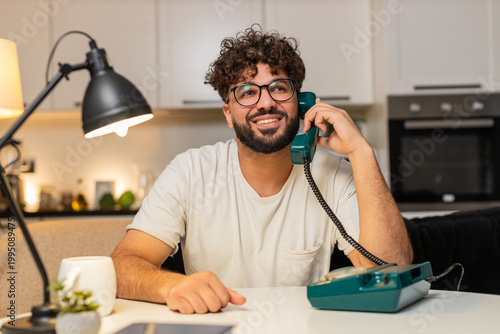 Slika na platnu Arabian man at home on hotline talks on corded telephone listens asks brief questions solves issue