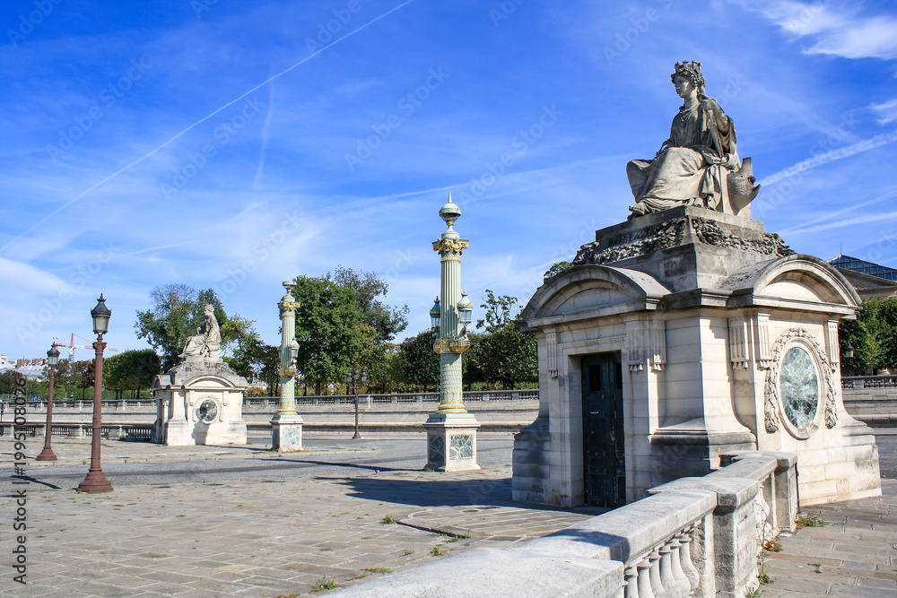 Fototapeta premium Ornate sculptures and classical architectural elements in central Paris. Elegant historic design with columns and stone structures under clear blue sky.