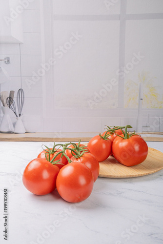 Tomatoes, beautiful red tomatoes in rustic bowls on a very bright kitchen counter, selective focus.