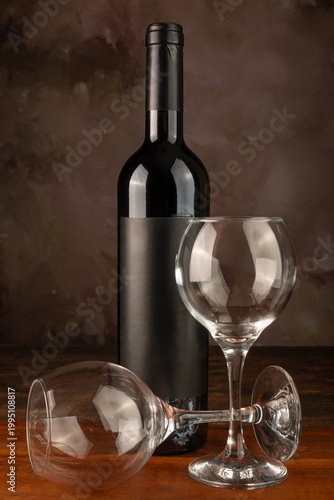 Bottle and wine glass, bottle and wine glass on a rustic wooden surface and abstract background, low key photo, selective focus.