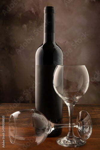 Bottle and wine glass, bottle and wine glass on a rustic wooden surface and abstract background, low key photo, selective focus.