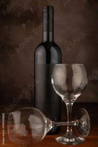 Bottle and wine glass, bottle and wine glass on a rustic wooden surface and abstract background, low key photo, selective focus.