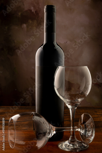 Bottle and wine glass, bottle and wine glass on a rustic wooden surface and abstract background, low key photo, selective focus.