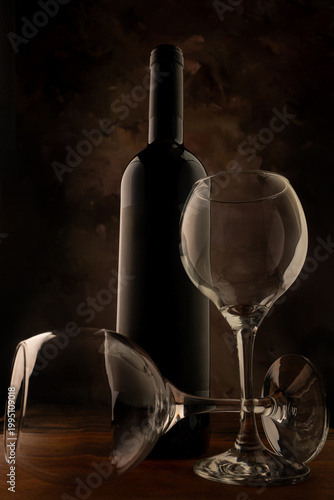 Bottle and wine glass, bottle and wine glass on a rustic wooden surface and abstract background, low key photo, selective focus.