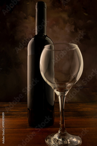 Bottle and wine glass, bottle and wine glass on a rustic wooden surface and abstract background, low key photo, selective focus.