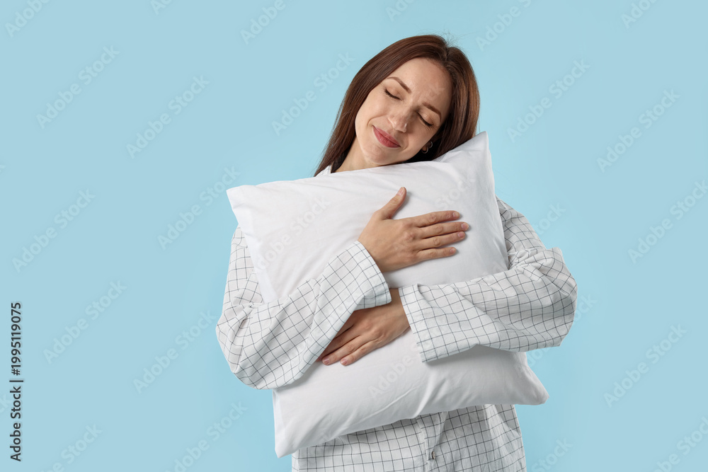 Fototapeta premium Beautiful woman with pillow on light blue background. Space for text