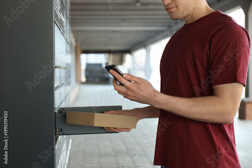 Fotografie Courier putting cardboard box into parcel locker outdoors, closeup