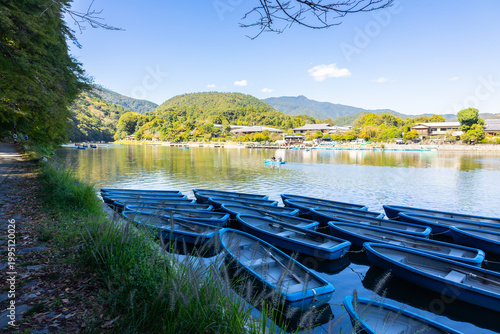 Traditional sightseeing boat sailing on river in Kyoto near Arashiyama and Togetsukyo bridge in Kyoto, Japan 