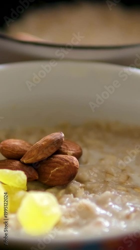 Woman hand add chia seeds into a bowl of greek yogurt with oat granola, banana, blueberries and almonds on gray background