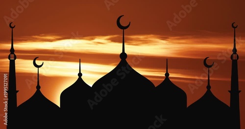 Silhouette of a mosque and minarets against the backdrop of sunrise.