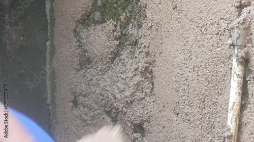 A construction worker is plastering a wall using a cement trowel on a house wall.