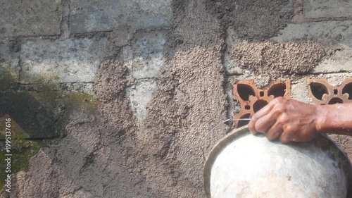 A construction worker is plastering a wall using a cement trowel on a house wall.