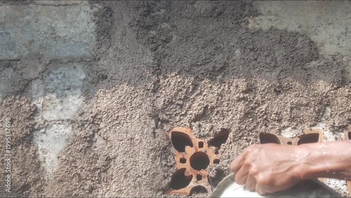 A construction worker is plastering a wall using a cement trowel on a house wall.