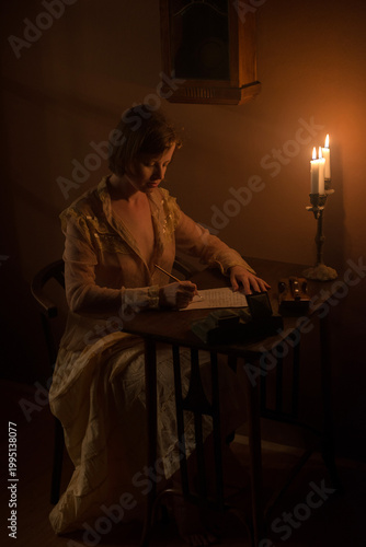 Young woman writing a letter under candle light
