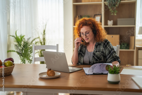 Fotografie Woman telecommuting customer service using headset and laptop at home