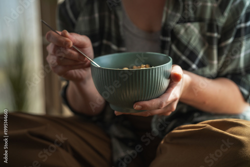 Foto Person eating healthy breakfast cereal granola in morning light