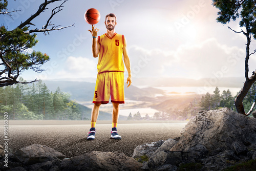 Basketball. A basketball player practices on a basketball court in the wilderness. A beautiful landscape is in the background.