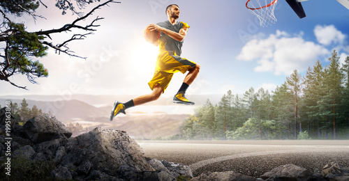 Basketball. A basketball player practices on a basketball court in the wilderness. A beautiful landscape is in the background.