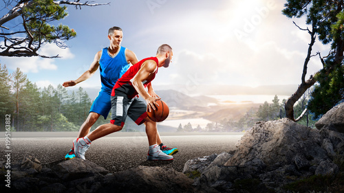 Basketball. Two basketball players practice on a basketball court in the wilderness. A beautiful landscape is in the background.