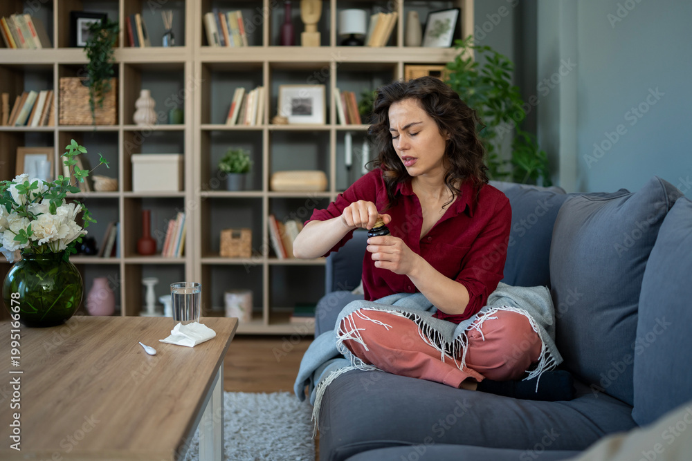 Obraz premium Young woman taking medicine at home feeling unwell