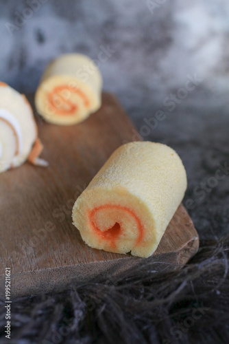 Swiss roll cake with fresh cream served on wooden plank. Fluffy dessert and bakery. 