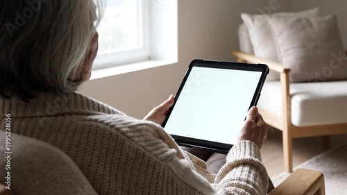 Elderly Woman Using a Tablet Computer in a Cozy Living Room, Mockup Screen for Content Creation