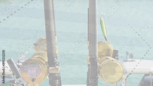 Two fishing rods and gold reels standing in holders while wind and boat sway moving lure