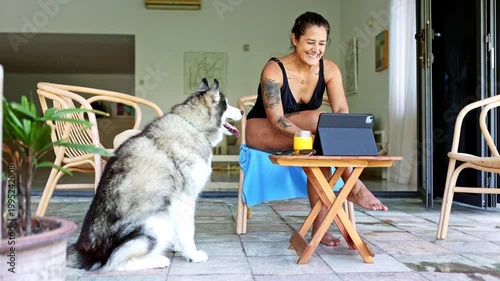 Digital nomad woman working on a tablet with her alaskan malamute dog