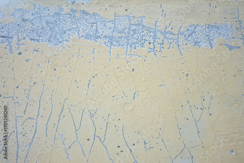 Yellow stained wall with cracks peeling paint grunge textured concrete abstract background pattern