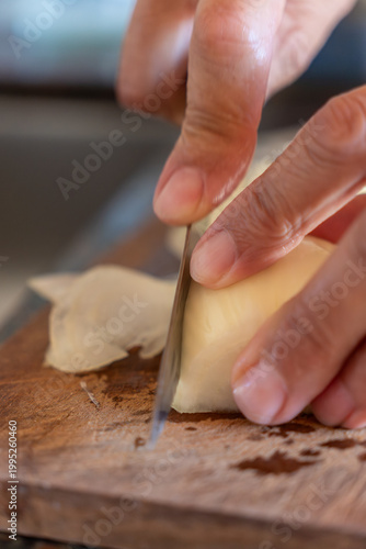 Close-up of Senior Woman Hands Slicing White Onion on Wooden Cutting Board