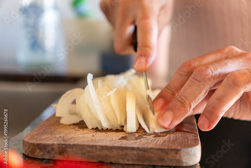 Close-up of Senior Woman Hands Slicing White Onion on Wooden Cutting Board