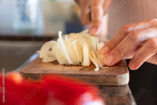 Close-up of Senior Woman Hands Slicing White Onion on Wooden Cutting Board