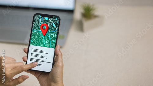 Foto Hand holding smartphone showing digital city map with red location pin on screen