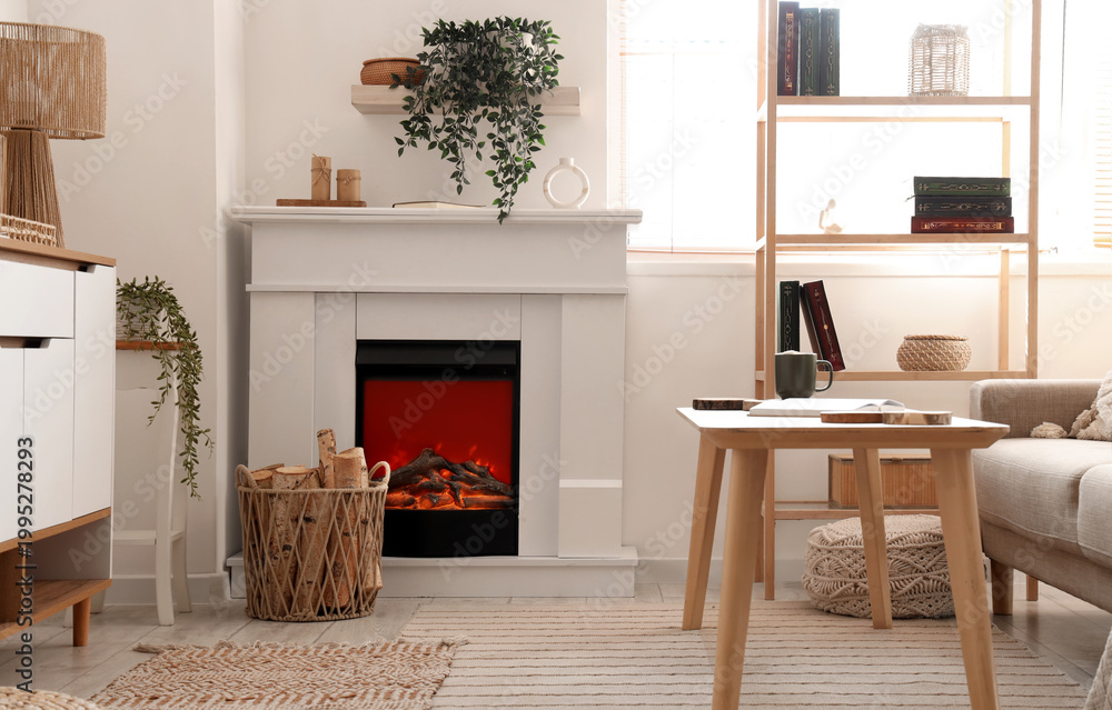 Fototapeta premium Interior of living room with commode, shelving unit, coffee table, fireplace and firewood in wicker basket