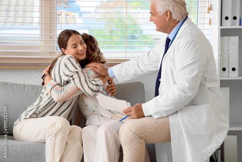 Young lesbian couple with fertility doctor hugging after IVF in clinic
