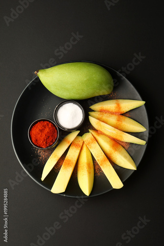  raw mango slices with chili powder and salt for tropical pickle preparation