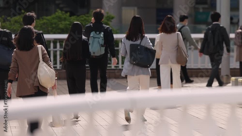 朝、出勤する若い女性の後ろ姿
