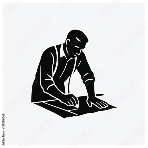 Silhouette of a man working on a blueprint or architectural plan.