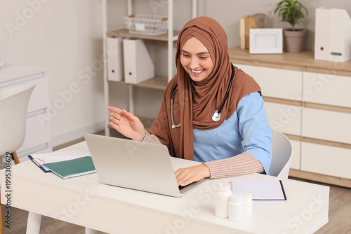 Foto Female Muslim doctor in hijab working with laptop at hospital