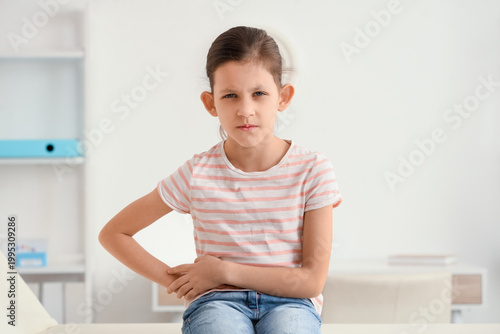 Teenage girl with appendicitis sitting on couch in clinic