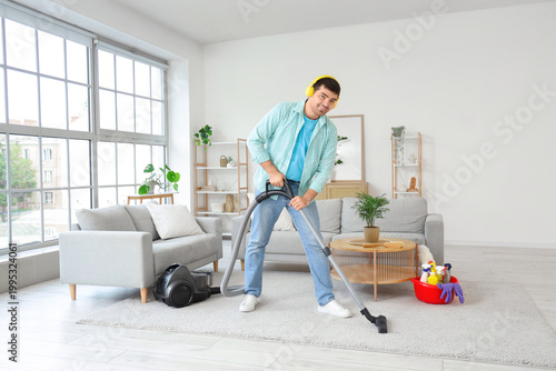 Young man vacuuming carpet ...