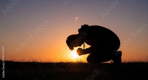 Silhouette of a person kneeling in prayer against a vibrant sunset sky