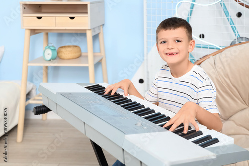 Foto Cute little boy playing synthesizer in bedroom