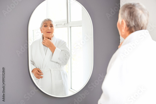 Senior woman near mirror in bathroom